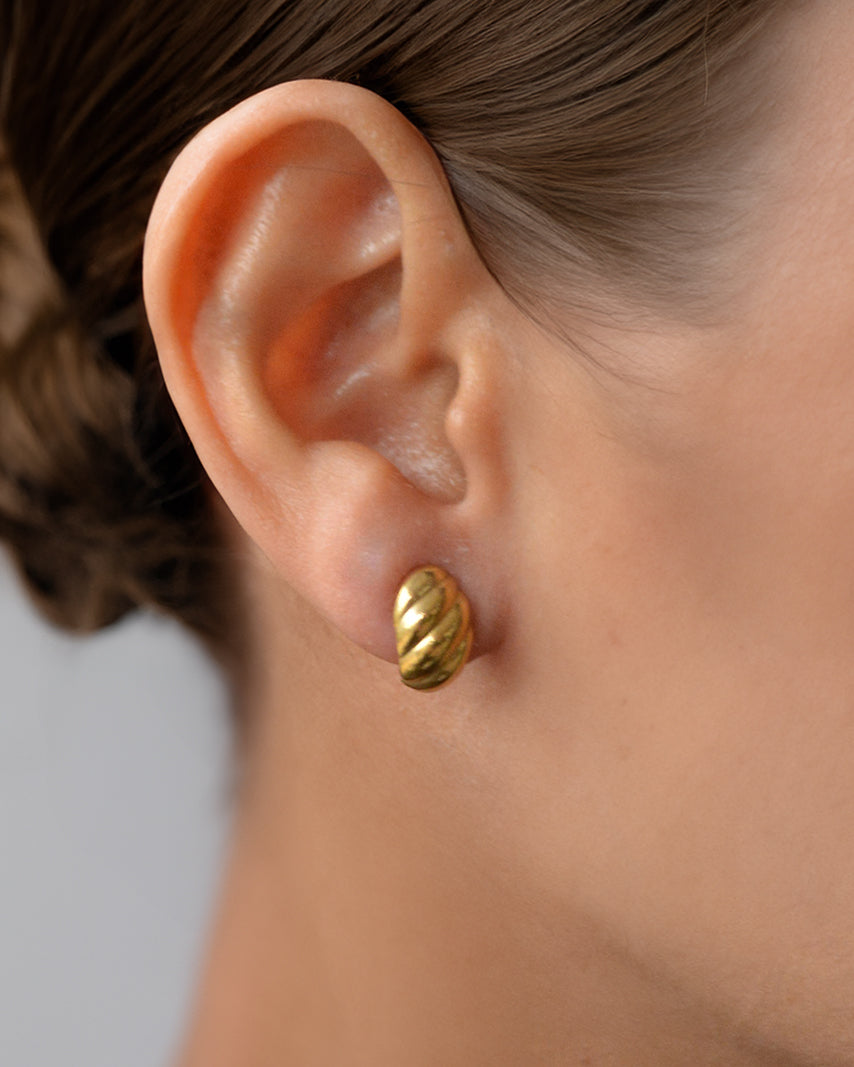 Lia spiral gold earrings worn on ear – waterproof and perfect for daily wear