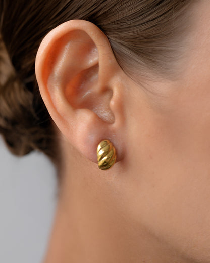 Lia spiral gold earrings worn on ear – waterproof and perfect for daily wear